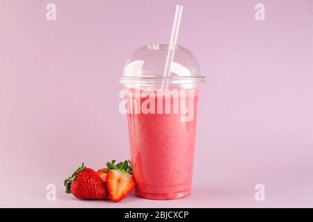 Delicious strawberry milkshake in plastic cup on pink background Stock Photo