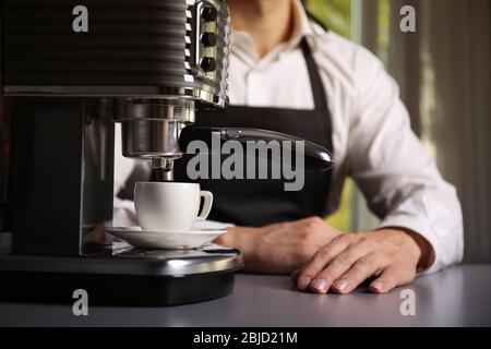 Male barista making fresh espresso in coffee maker Stock Photo