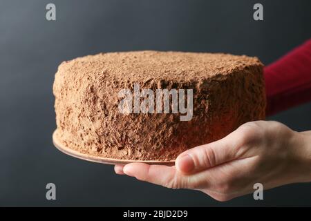 Woman holding chocolate cake on dark background Stock Photo