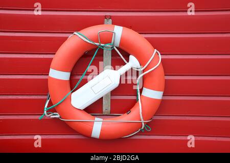 Orange red life saving ring against a red painted wooden wall, with white string, Iceland. Stock Photo