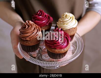 Woman holding glass stand with tasty chocolate cupcakes, close up Stock Photo