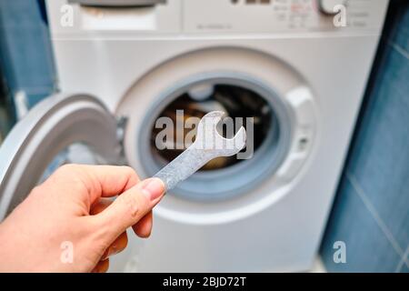 The concept of repairing a washing machine by worker in the bathroom. Close up. Stock Photo