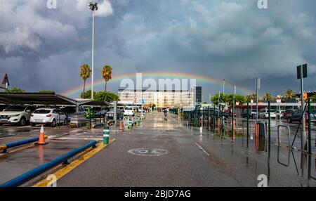 Rainbow and reflections in the water at the Barcelona airport parking Stock Photo