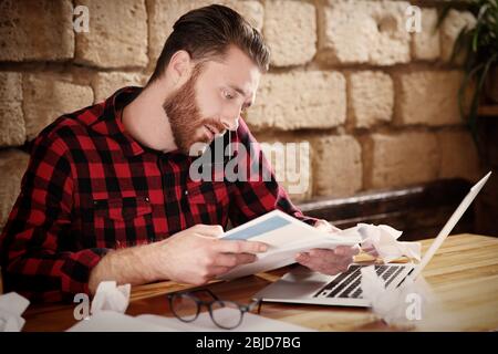 Handsome young man working on computer at cafe Stock Photo