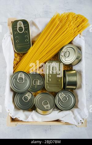 Top view of a box with various cans of non-perishable food and pasta such as spaghetti. Keep food at home for situations such as quarantine due to Cov Stock Photo