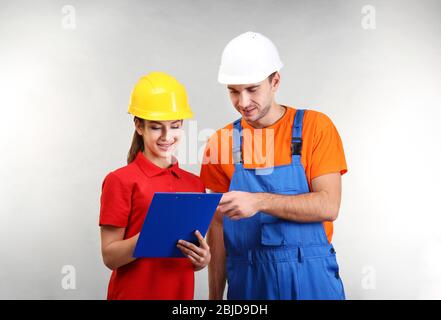 Warehouse workers with clipboard discussing something, on light background Stock Photo
