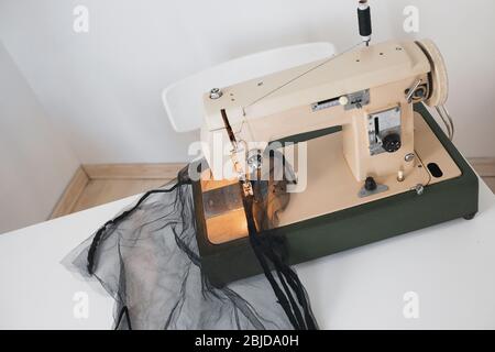 Sewing process f dress from black textile mesh fatinon the sewing machine at home in the workplace on a white background Stock Photo