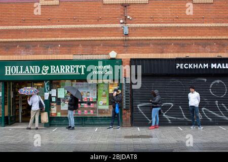 Peckham, UK. 29th April, 2020. Life in South London during the Coronavirus lockdown. People queue outside health shop Holland & Barrett in Peckham. ( Credit: Sam Mellish/Alamy Live News ) Stock Photo
