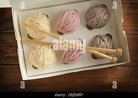 Balls of knitting yarn in box on wooden background Stock Photo