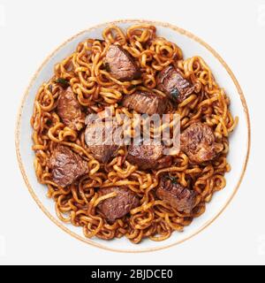 Ram-Don or Chapaguri noodles with beef steak in bowl isolated on white background. Jjapaguri is a popular south korean dish with ramen and udon noodle Stock Photo