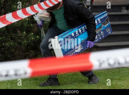 Gelsenkirchen, Germany. 29th Apr, 2020. An investigator walks under the flutter tape with a cardboard box depicting a rifle after leaving the suspect's apartment. A police officer was killed on Wednesday morning during a SEK operation in Gelsenkirchen. Credit: Bernd Thissen/dpa/Alamy Live News Stock Photo