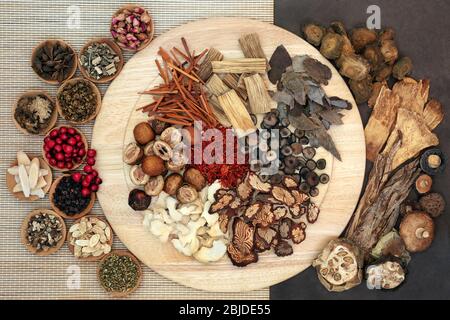 Chinese  herbs & spice used in traditional herbal medicine on a wooden board, bamboo & lokta paper. Flat lay. Stock Photo