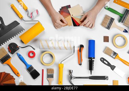 Decorator holding a color swatches. Painting tools all around on table