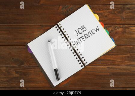Job interview concept. Opened notebook and felt pen on wooden table Stock Photo