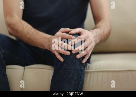 Man suffering from knee pain at home, closeup Stock Photo