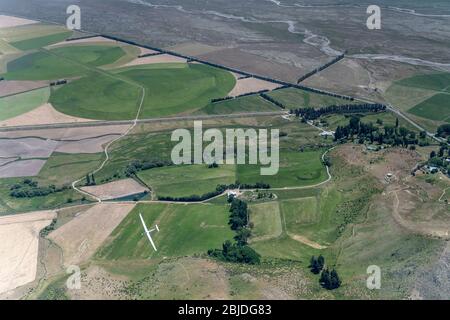 aerial, from a glider, of another glider flying over green countryside near Omarama, shot in bright spring light, Canterbury, Otago, South Island, New Stock Photo