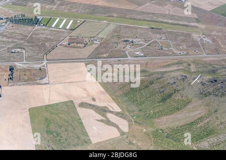 aerial, from a glider, of another glider flying over mt. St. Cuthbert range barren slopes near airfield, shot in bright spring light at Omarama, Cante Stock Photo