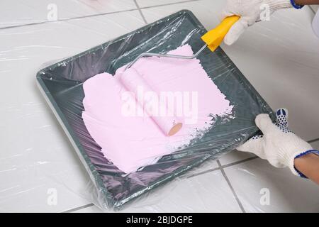 Worker using paint roller and tray while making repair, closeup Stock Photo
