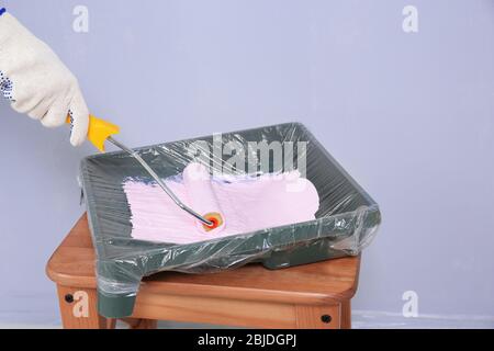 Worker using paint roller and tray while making repair, closeup Stock Photo