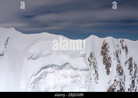 aerial, from a glider, with snow landslides at  Mt. Cook range summit, shot in bright spring light from west, Canterbury, South Island, New Zealand Stock Photo