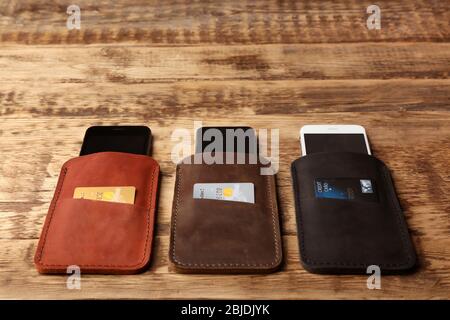 Leather cases with mobile phones and credit cards on wooden background Stock Photo