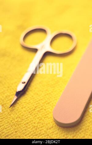 Set of tools for manicure. Scissors and nail file on the yellow table closeup Stock Photo