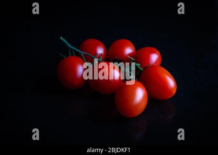 Piccadilly tomato bunch. Fresh juicy sweet tomatoes for traditional Mediterranean cuisine. Black background. Stock Photo