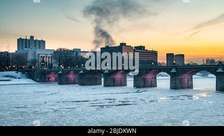 Ice flows down the Suquehanna River under the Market Street Bridge in Harrisburg, PA  during a winter sunrise Stock Photo