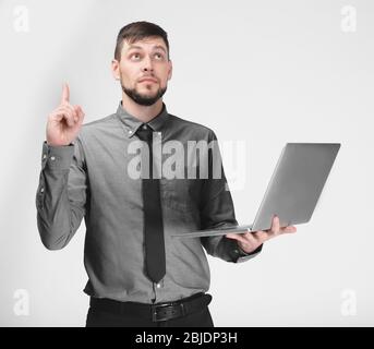 Handsome young programmer with laptop on color background Stock Photo