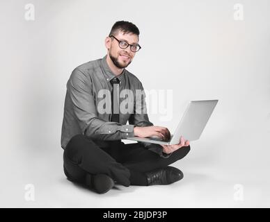 Handsome young programmer with laptop on light background Stock Photo