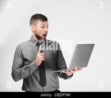 Handsome young programmer with laptop on color background Stock Photo