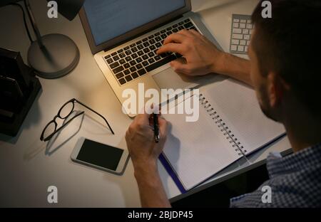 Young programmer working at home late in evening Stock Photo