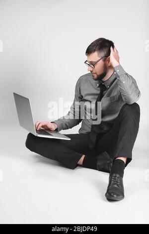 Handsome young programmer with laptop on light background Stock Photo