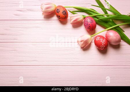 Colourful Easter eggs with floral ornament and fresh tulips on pink wooden background Stock Photo