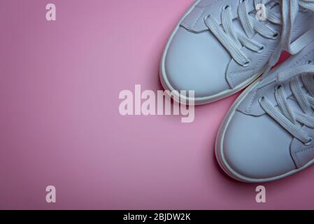 White sneakers on the pale pink background. Flat lay. Copy space. Place for text.Abstract surrealism and minimalism shopping concept. Stock Photo