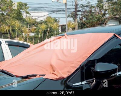 Red fabric covered on car front window for heat protection from sunshine. Car sunshade front windshield sunscreen simple style. Stock Photo