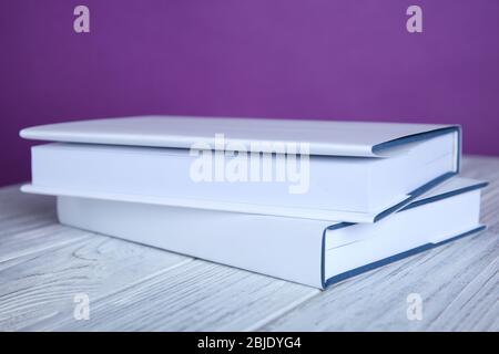 Two books on wooden table against purple background Stock Photo