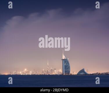 Viewing Dubai cityscape across the sea after sunset. Dubai, United Arab Emirates. Stock Photo