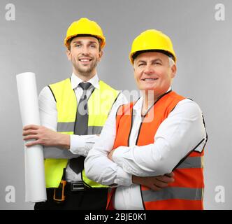 Handsome engineer and senior worker on light background Stock Photo