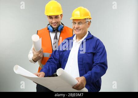 Handsome engineer and worker with drawings of new project, on light background Stock Photo