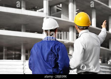 Engineer and worker discussing construction of unfinished building Stock Photo