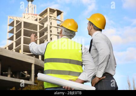 Engineer and worker discussing construction of unfinished building Stock Photo