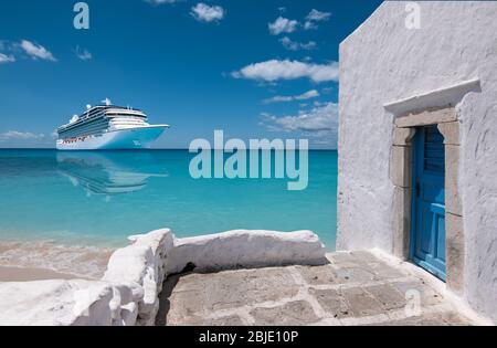 Cruise ship in Mykonos, Greece, Europe. Luxury Greek travel vacation with whitewashed architecture and blue door. Luxury white cruise vessel on the se Stock Photo