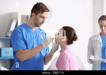 Plastic surgeon applying marks onto young woman's face prior to operation Stock Photo