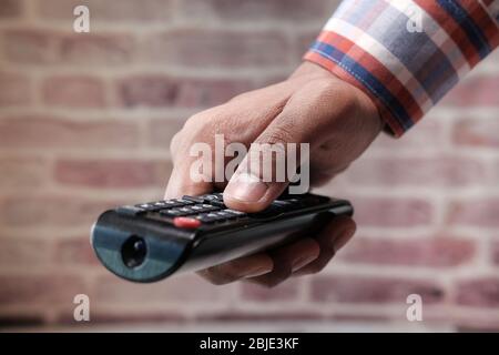 close up of man's hand using tv remote Stock Photo