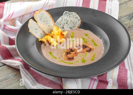 Cream of mushroom soup in dark bowl. Homemade creamy soupe with sliced boletus mushrooms. Stock Photo