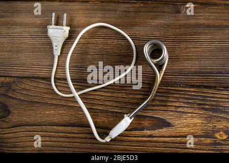 Old immersion water heater on dark wooden background. Close-up Stock Photo