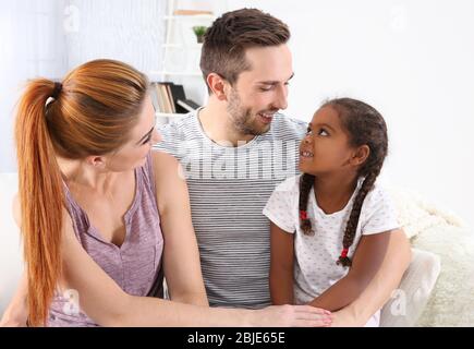 Happy interracial family sitting on sofa Stock Photo