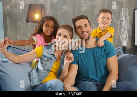 Happy interracial family sitting on sofa Stock Photo