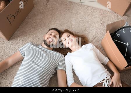 Happy family couple lying with cardboard boxes at home Stock Photo